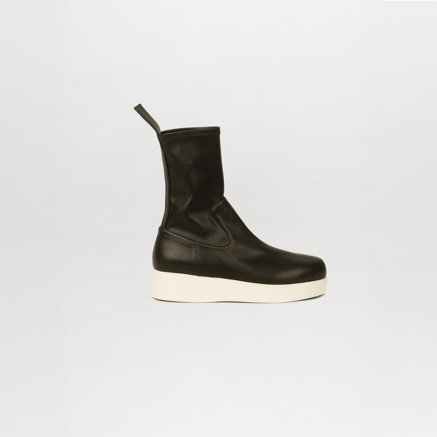 The Baia Boots Black are stretch calf leather boots with a black and white design, pull tab at the back, and thick white sole, shown on a plain white background.