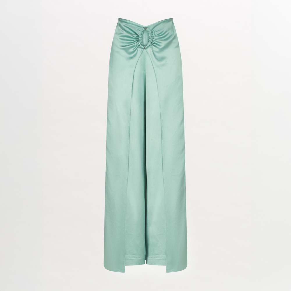 The Belma Pant in light green satin features a draped front, gathered knot at the waist, subtle oval ring detail, and a chic front slit, shown against a plain white background.