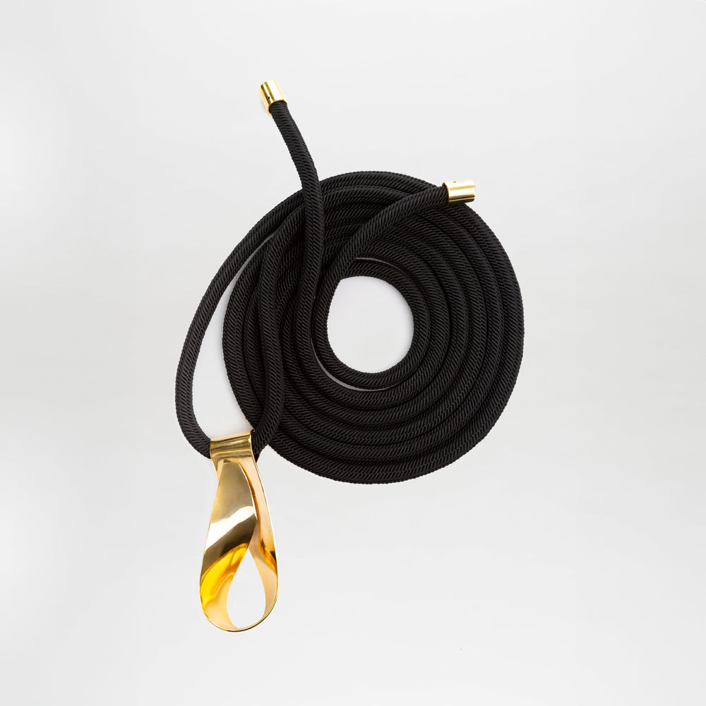 The Daiana Belt is a black cord belt featuring a gold handle and crafted from premium Italian material.