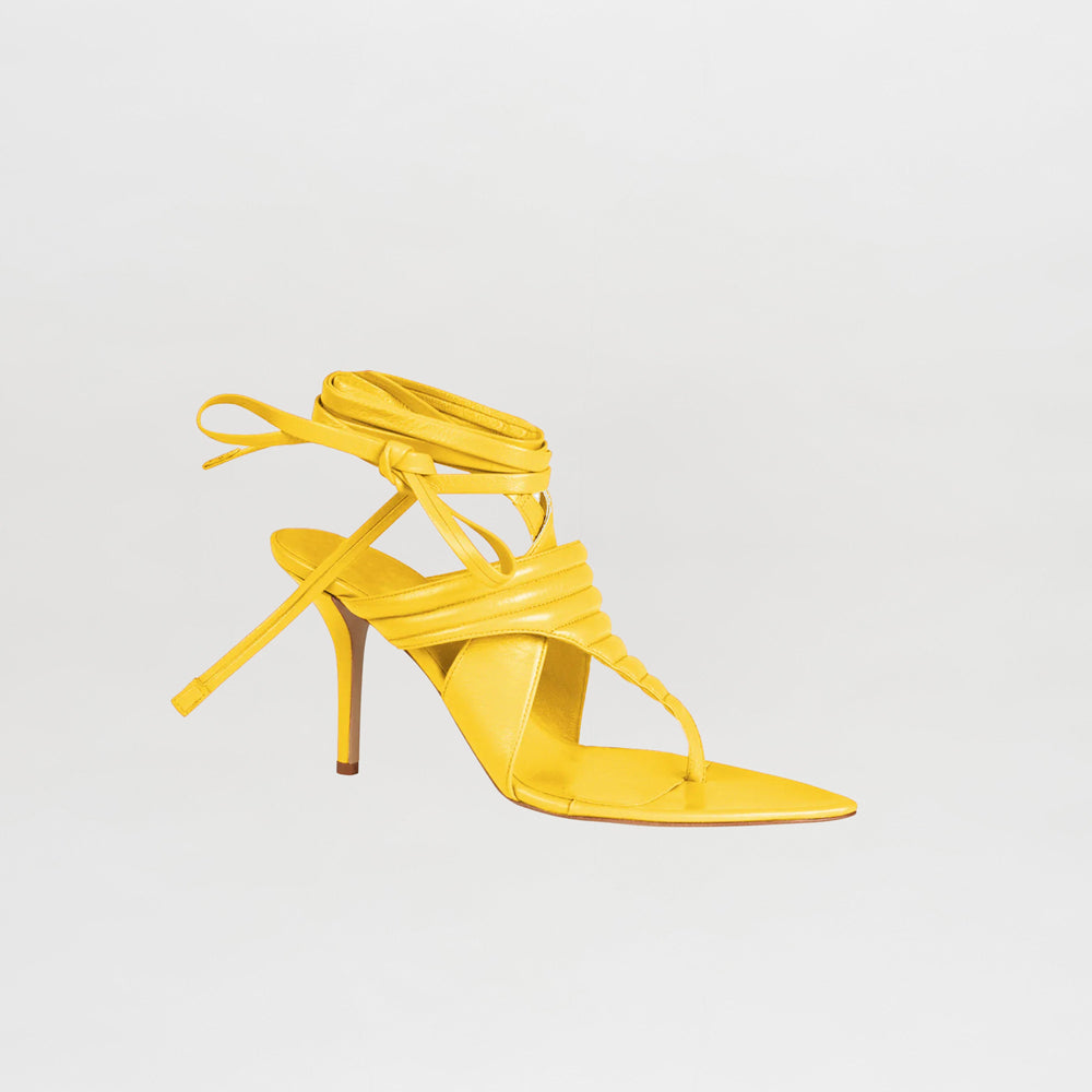 The Dalila Heels Limoncello are yellow high-heeled sandals with a pointed toe, thin stiletto heel, open-toe design, and wrap-around ankle straps, showcased against a plain light background.