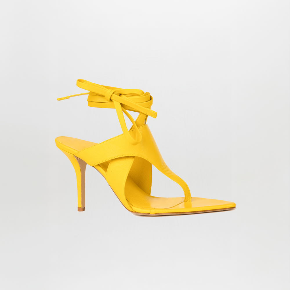The Domenico Heels Limoncello by GIA Couture are yellow Italian leather sandals featuring a thong toe, ankle wrap straps, and a stiletto heel, showcased on a plain white background.