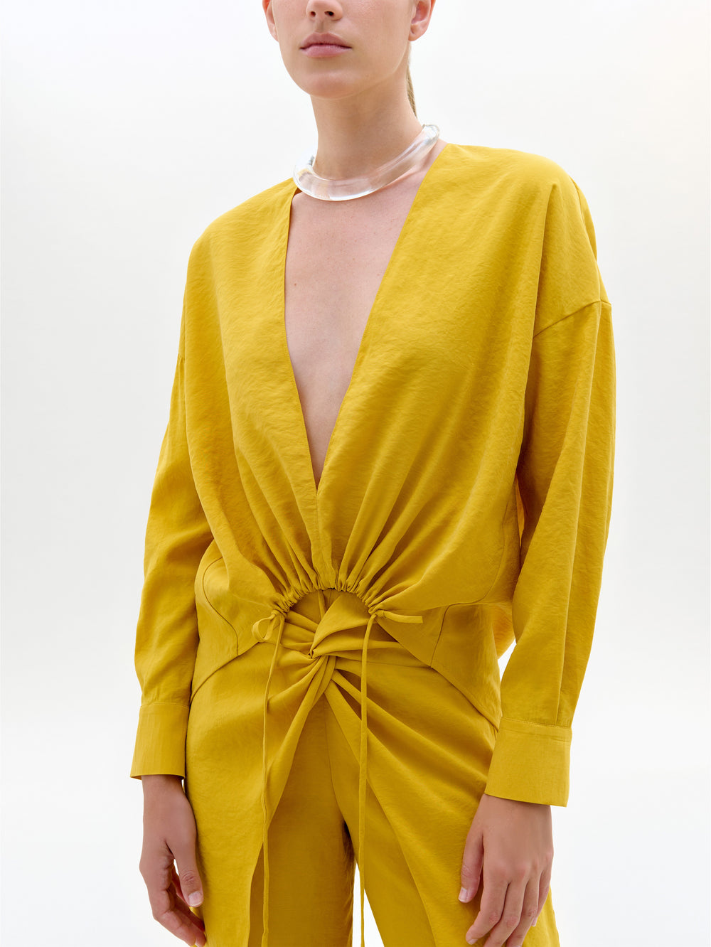 Yellow jumpsuit worn by a model on a white background