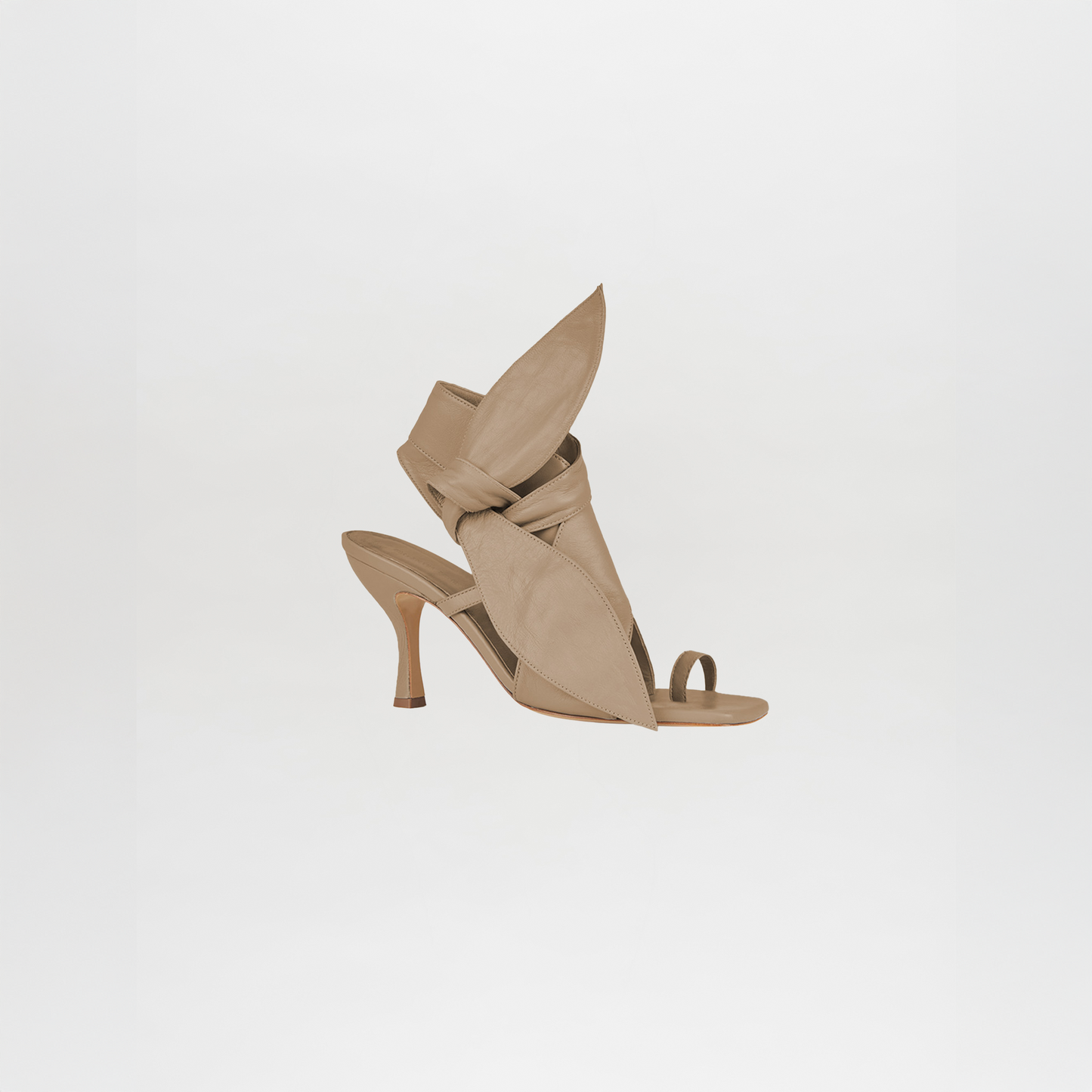 The Marco Heel Camel is a high-heeled, open-toe sandal crafted from beige Italian calf leather, featuring a distinctive sculptural upper with pointed and folded design elements.