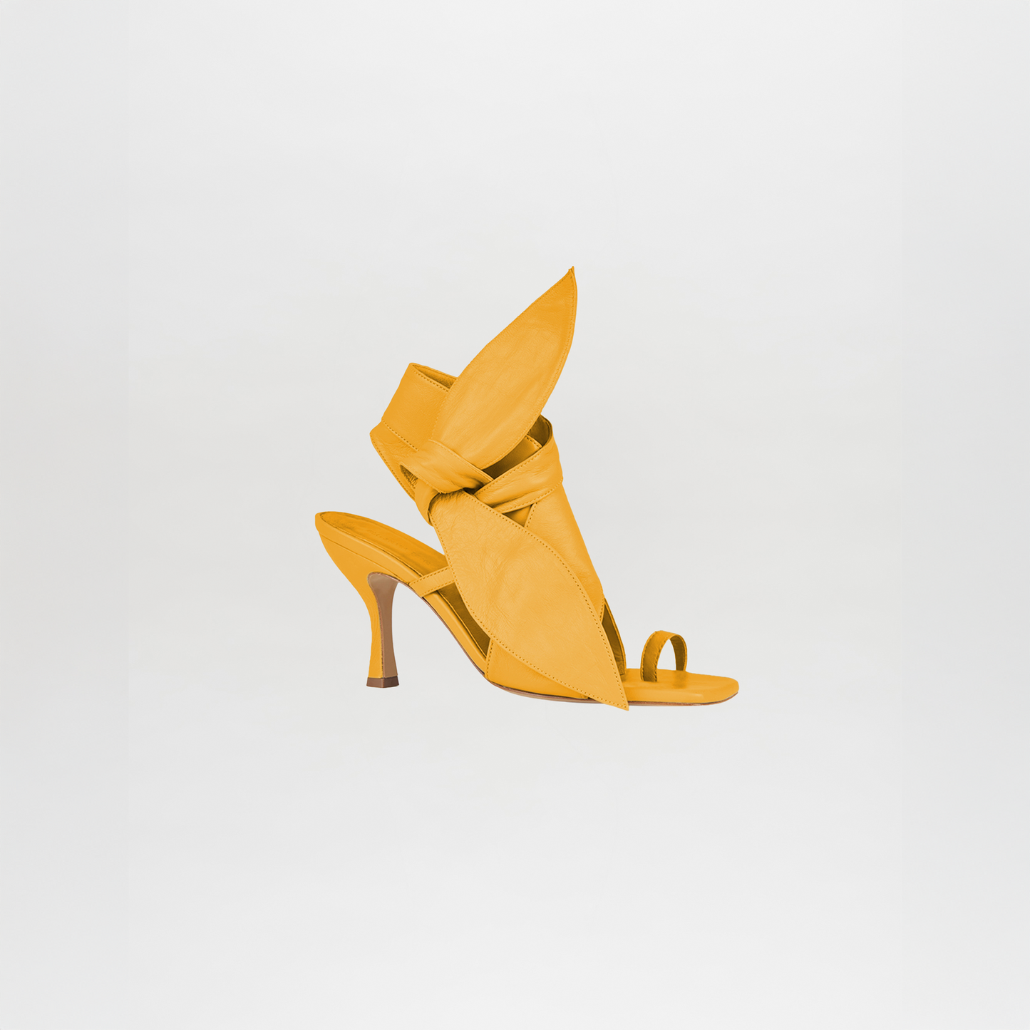 The Marco Heel Yellow is a bright yellow high-heeled sandal with comfortable crisscross straps, an open toe, and bold leaf-inspired accents.
