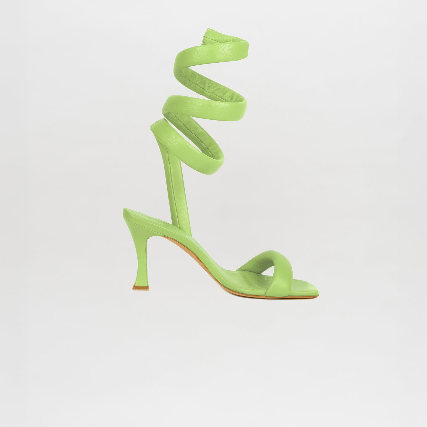 The Mika Heels Green by Silvia Tcherassi are bright green Italian calf leather heels with a single toe strap and a long, coiled ankle strap. They stand out elegantly against a plain white background.