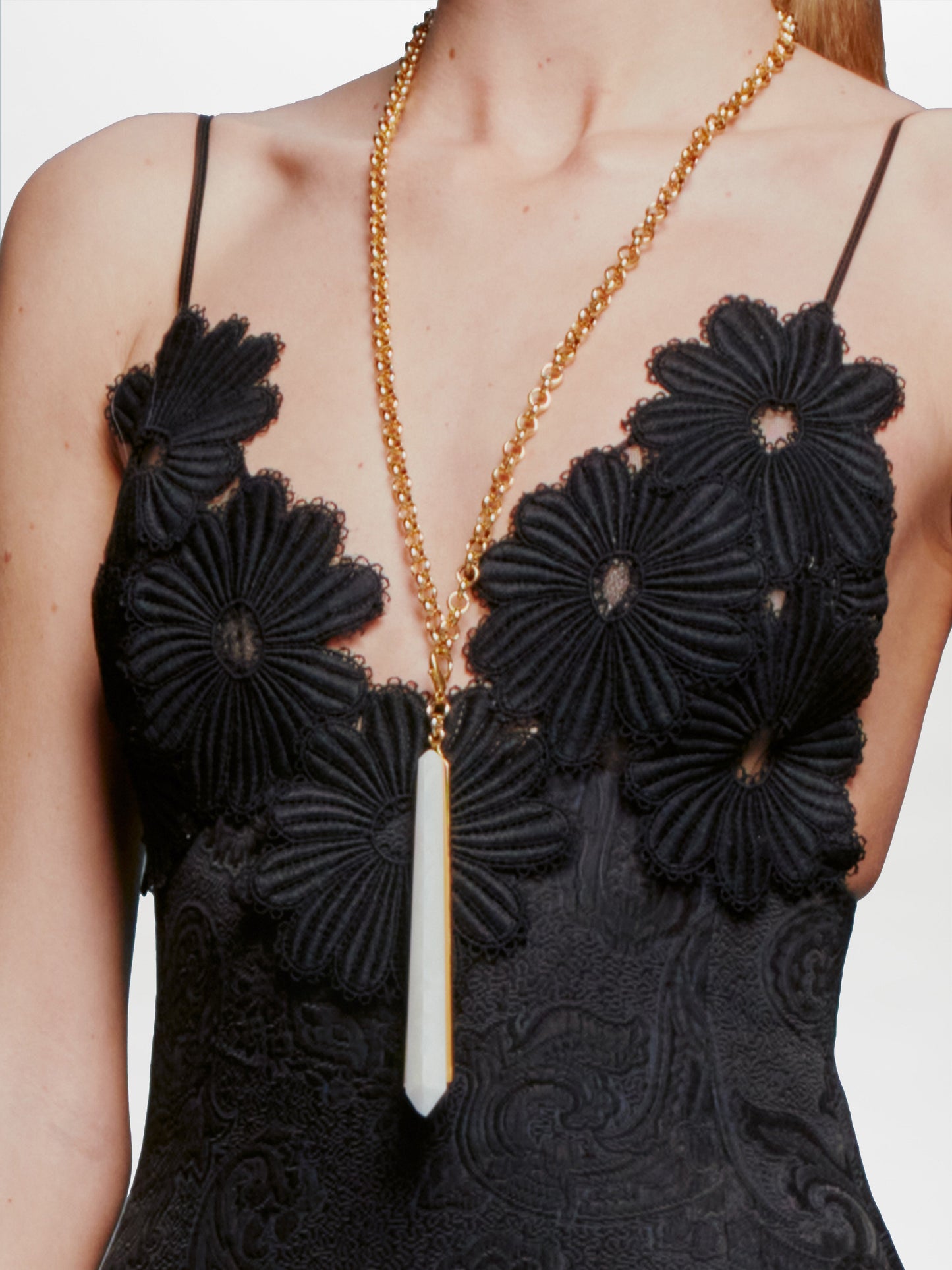 The Montse Charm features a long, pointed crystal pendant with a gold-plated brass clasp, set against a plain white background.