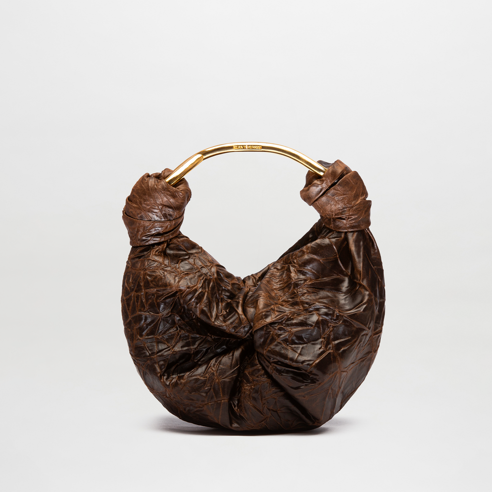 Brown leather handbag with gold handle on a light gray background