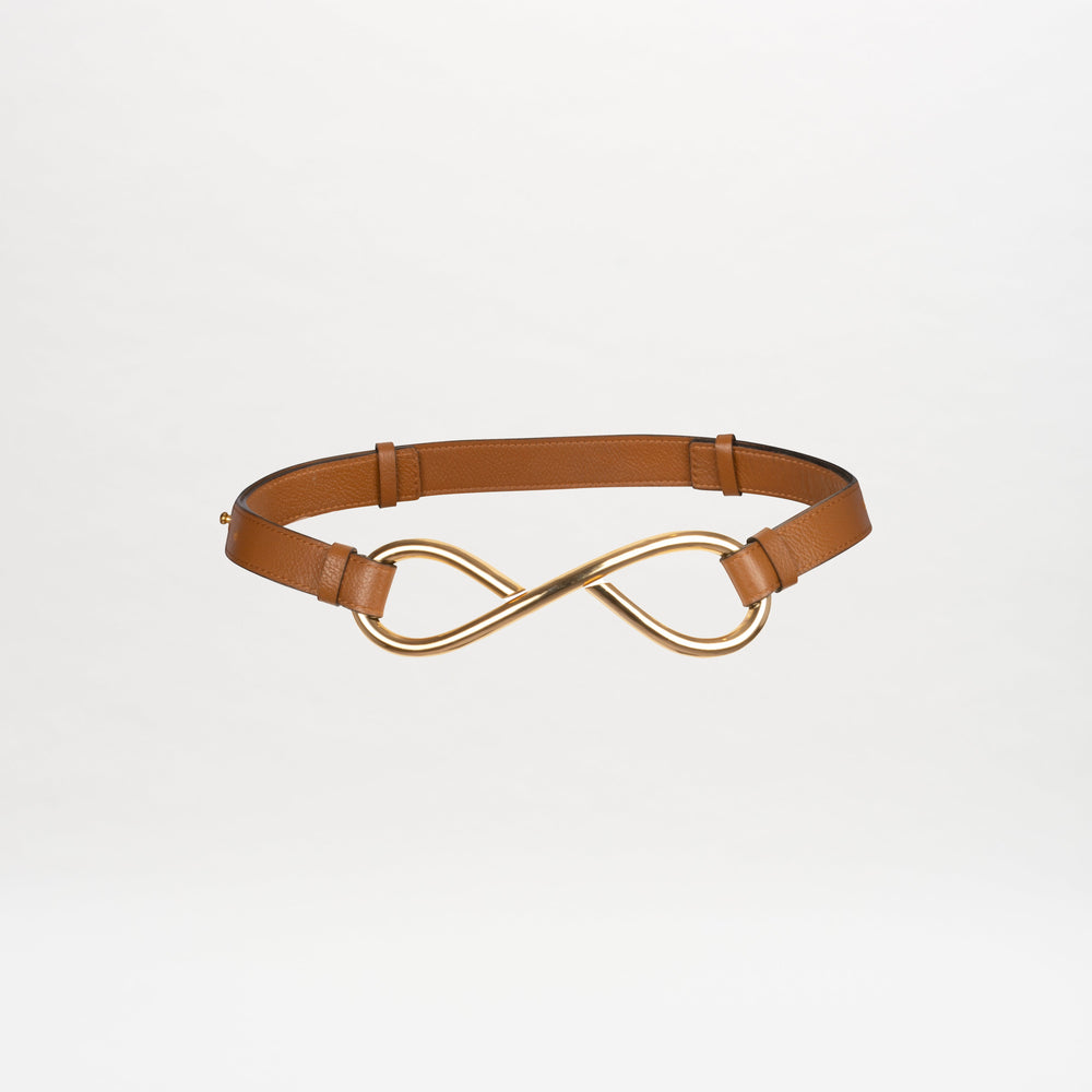 A Oihana Belt Camel with a gold infinity-shaped buckle centered in the middle, available for pre-order. It will ship by November 15th, 2024.