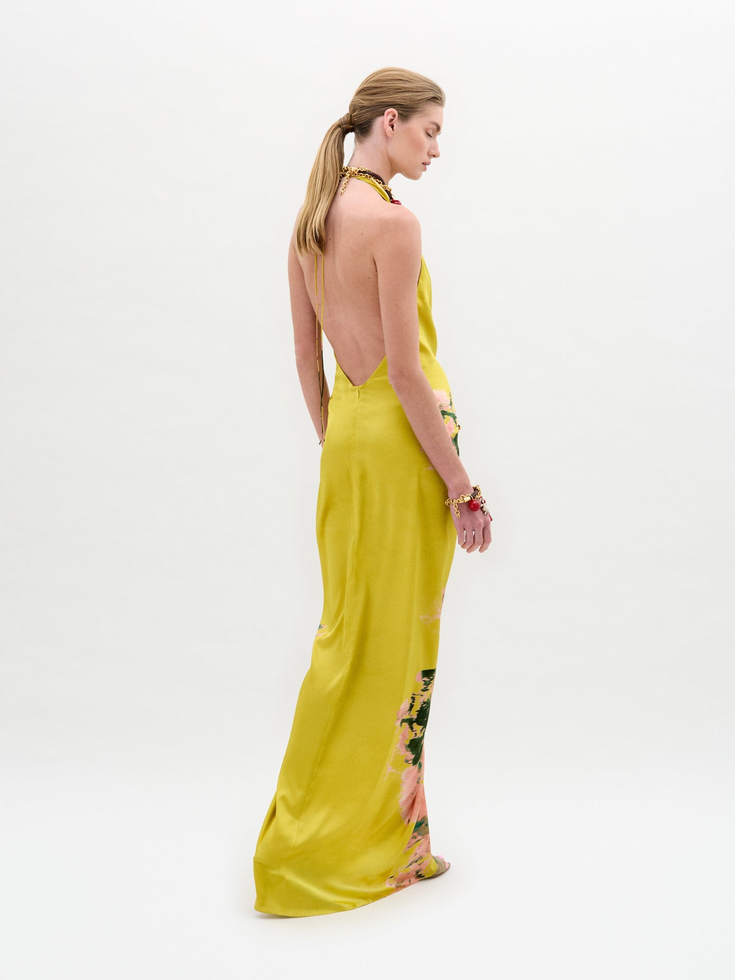 A person in the Sabrina Dress, a yellow and pink tie-dye style with a knotted front, holds a cream bag against a plain background.