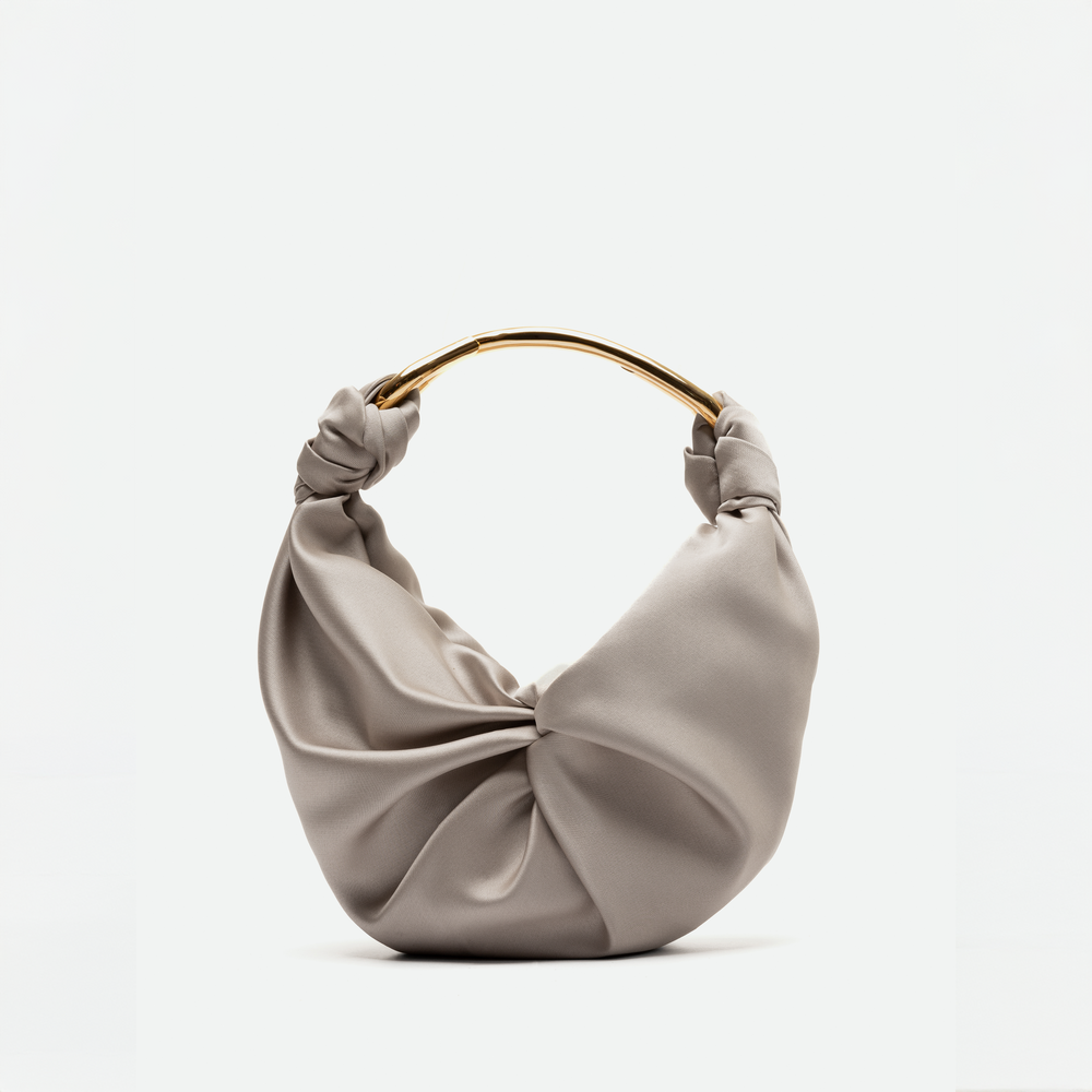 A beige satin handbag with a soft, ruched design and a gold metal handle. This elegant piece is available for pre-order and will ship between November 15 and December 15. The background is plain white.
Replace "beige satin handbag" with "Sofia Bag (Small) Beige":
The Sofia Bag (Small) Beige with a soft, ruched design and a gold metal handle. This elegant piece is available for pre-order and will ship between November 15 and December 15. The background is plain white.