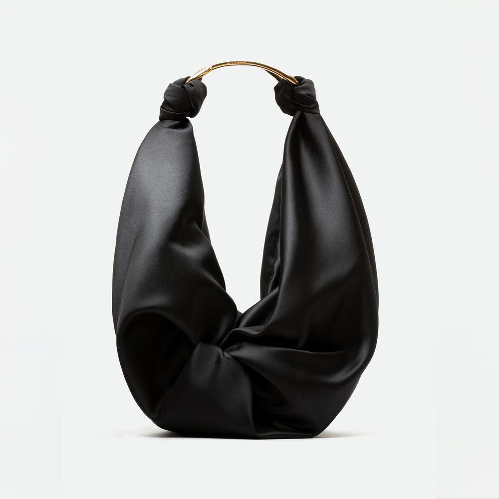 A Sofia Bag (Maxi) Black with a draped fabric design, featuring a metallic gold handle at the top, available for pre-order now and set to ship in early 2024.