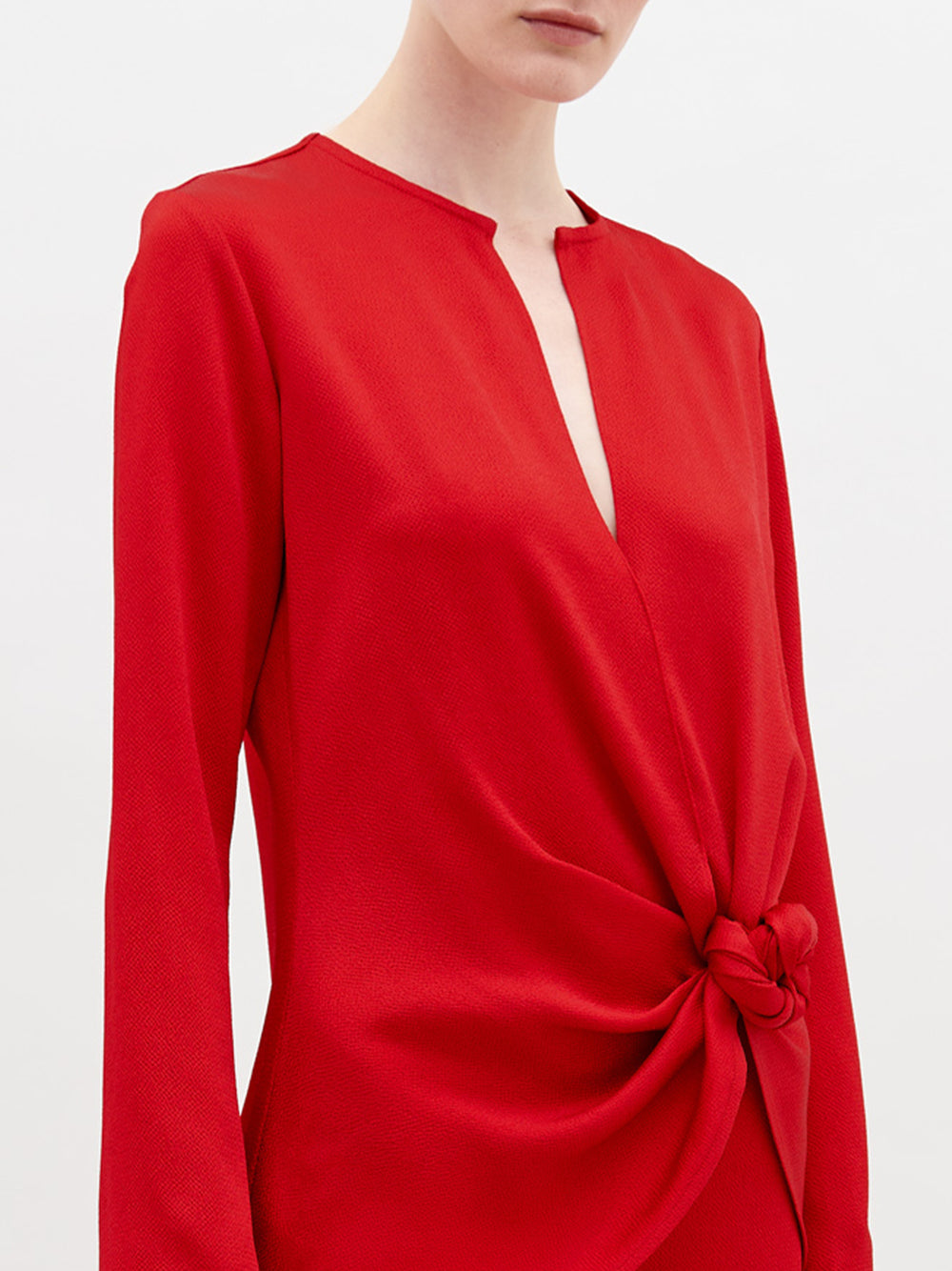 A person stands against a plain background wearing the Tayra Blouse in color Rouge