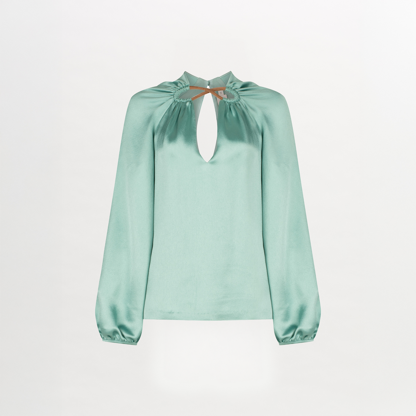 The Ximena Blouse is a light green silk top with long sleeves, a front keyhole neckline, gathered details, and subtle metallic accents.