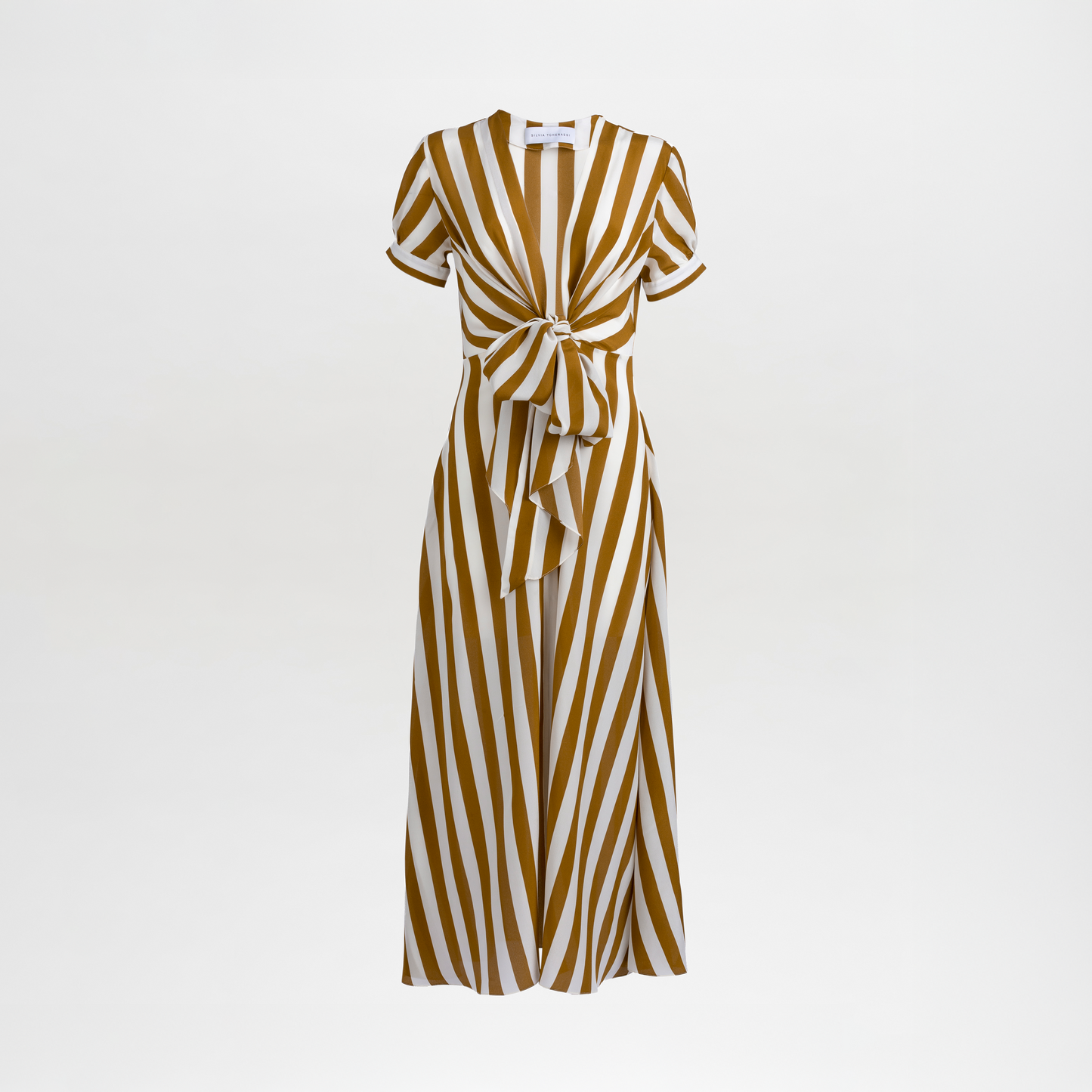 The Zila Dress, shown against a plain white background, is a brown and white vertically striped maxi dress with short sleeves, expertly crafted from luxurious 100% Italian silk. It features a V-neckline and a front tie detail.