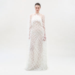 Woman wearing a long, sheer dress with floral patterns on a white background