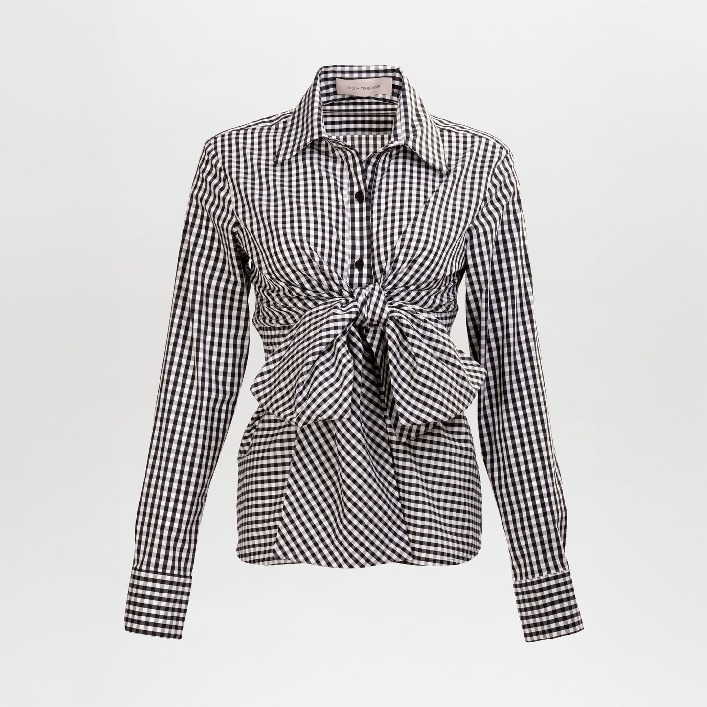 The Mercury Blouse is a long-sleeve black and white gingham shirt featuring a pointed collar and front knot detail at the waist, shown on a plain white background.