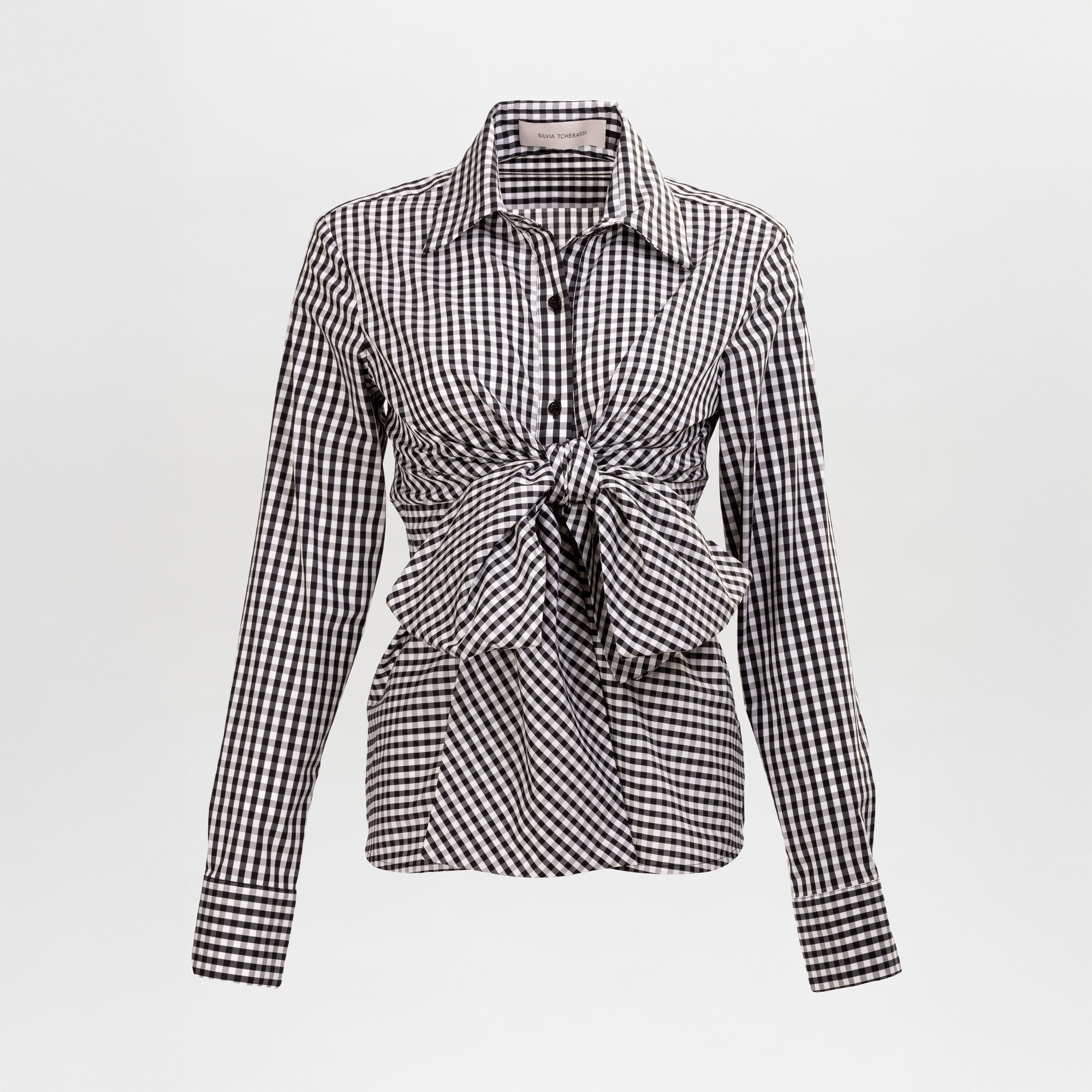 The Mercury Blouse is a long-sleeve black and white gingham shirt featuring a pointed collar and front knot detail at the waist, shown on a plain white background.