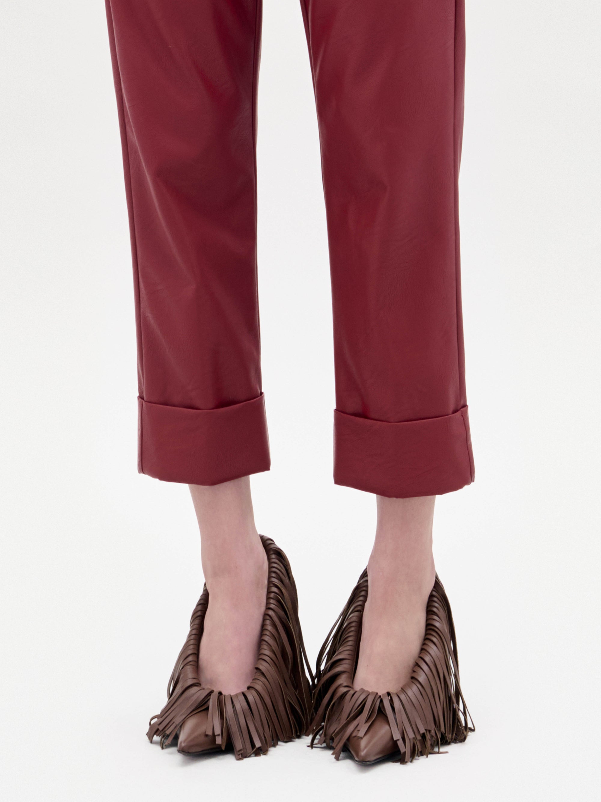 The Amelia Heels are brown pointed-toe high heels adorned with long, layered leather fringe, shown on a plain light grey background.