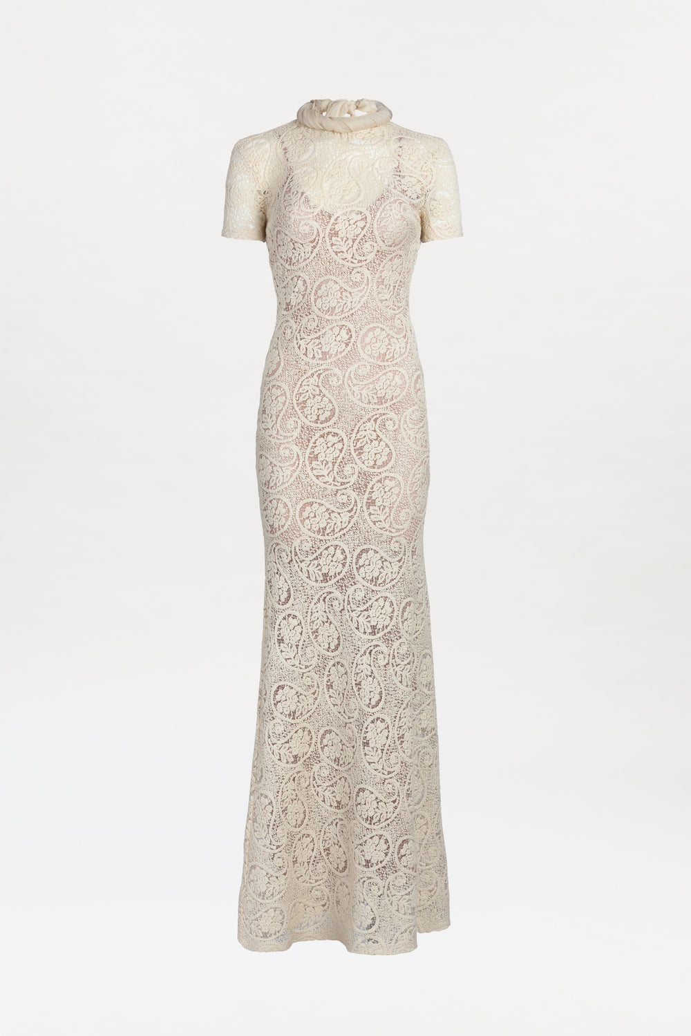 Tini Dress: An elegant, long cream lace dress featuring short sleeves, a high sheer neckline, and a fitted silhouette, displayed on a white background.