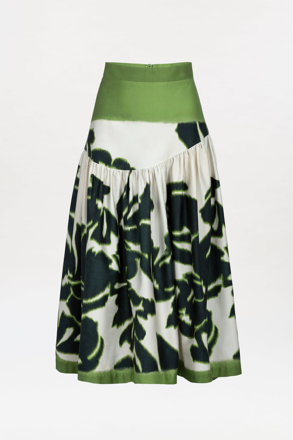 The Libby Skirt is a high-waisted, A-line skirt with a wide green waistband and hem, showcasing a white background adorned with large dark green floral patterns and subtle pleating.
