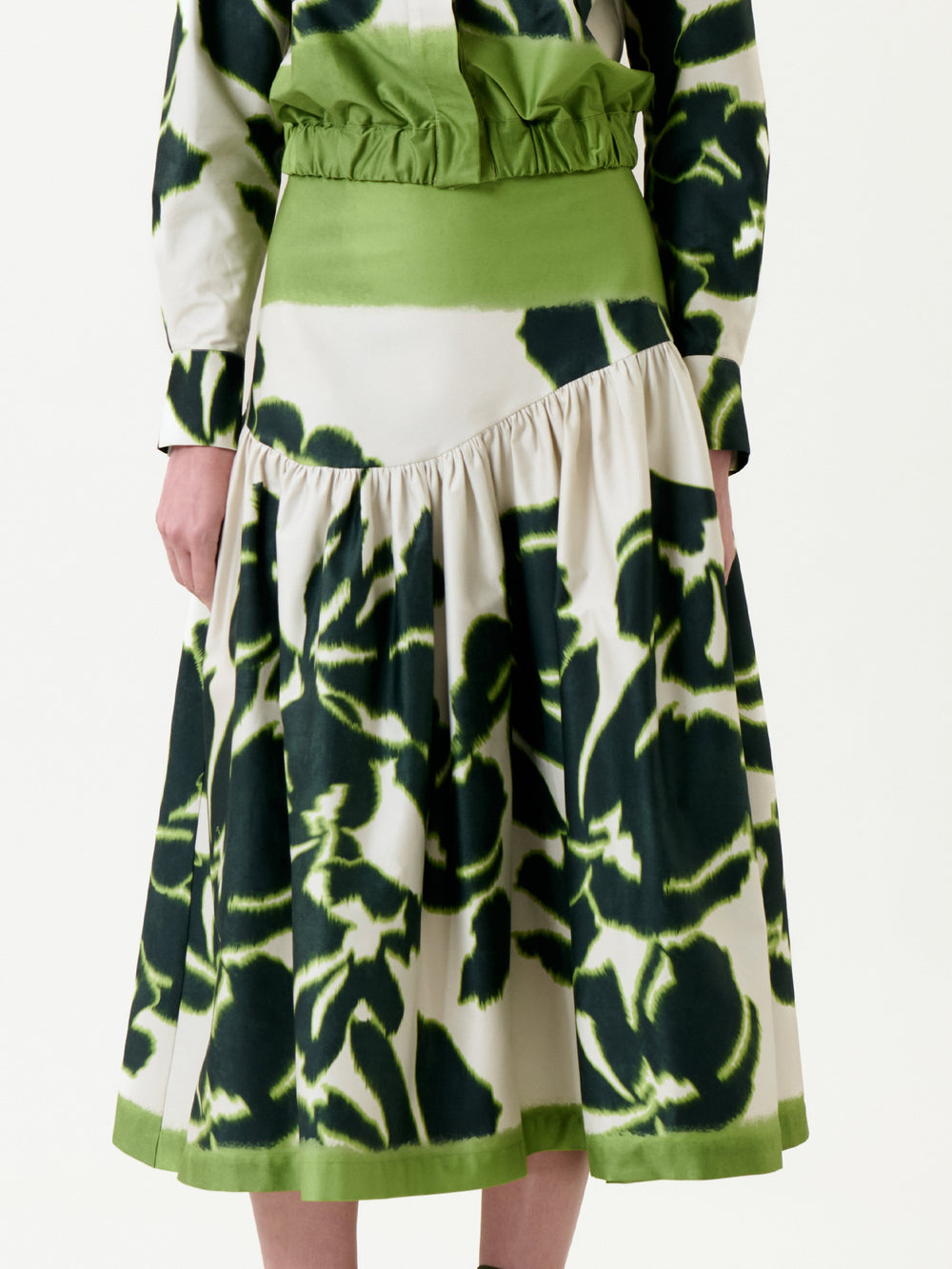 A person wearing the Libby Skirt, featuring a green and white tie-dye pattern with a gathered waist and flared hem; only the lower torso and upper legs are visible.
