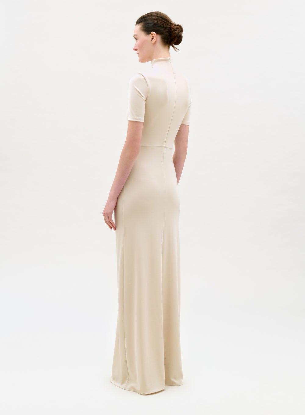 Woman wearing a long beige dress on a white background