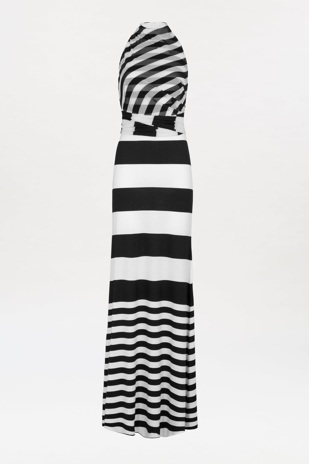 The Tove Dress is a sleeveless, floor-length design featuring black and white horizontal stripes of varying thickness. The top showcases diagonal stripes, while the skirt alternates thick and thin stripes, all set against a plain white background.