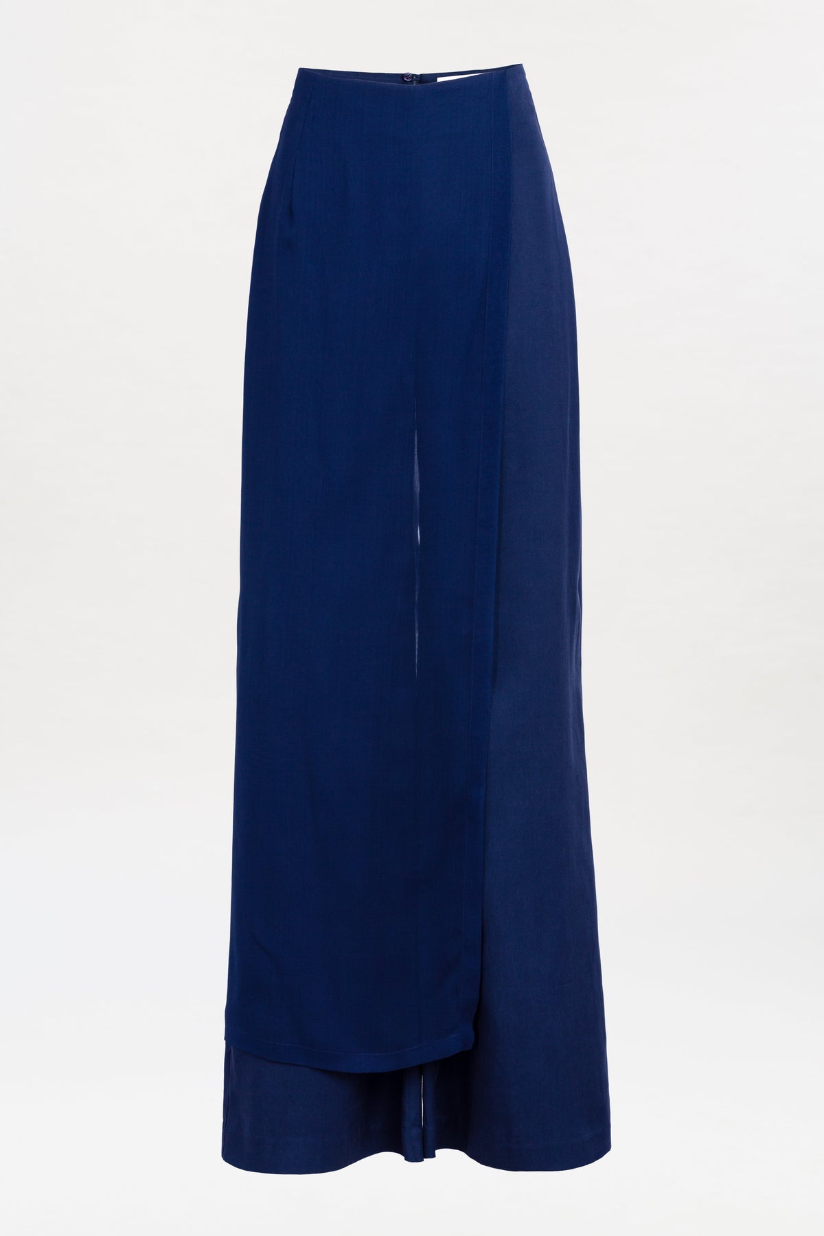 The Gaucin Pant is a long, high-waisted navy blue design featuring a subtle front overlap and a single button closure at the waistband, displayed against a plain white background.