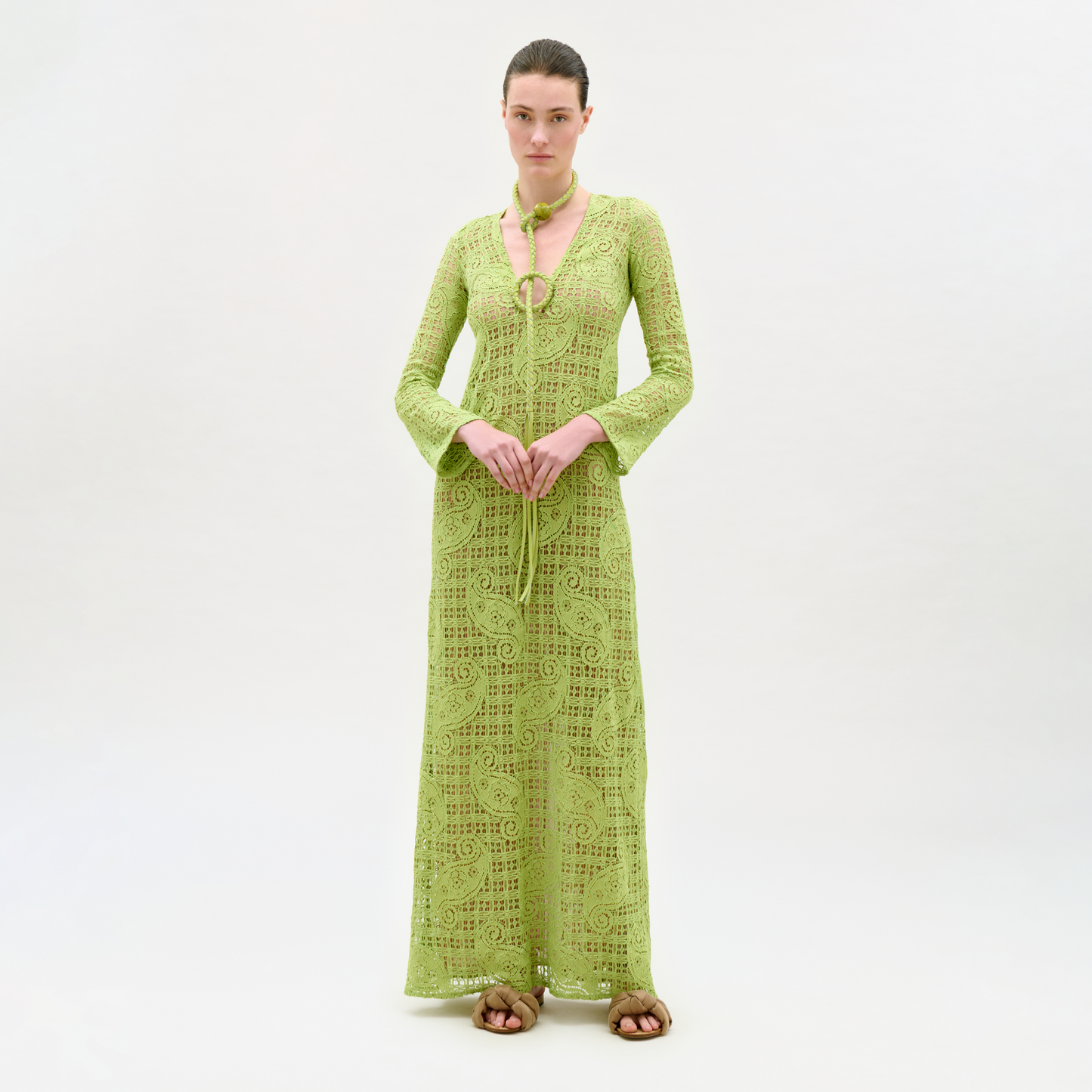 Woman wearing a green lace dress and cardigan on a white background