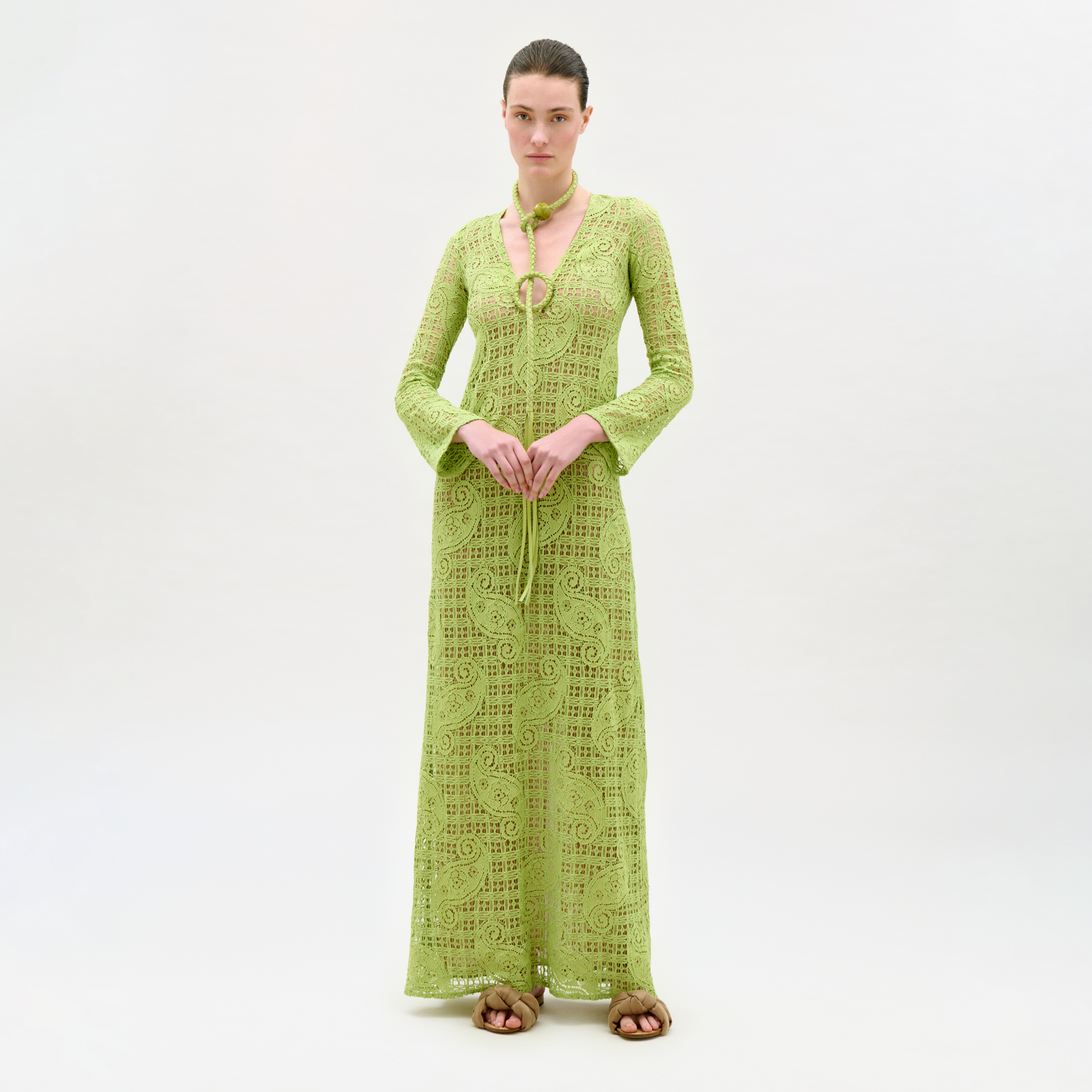 Woman wearing a green lace dress and cardigan on a white background