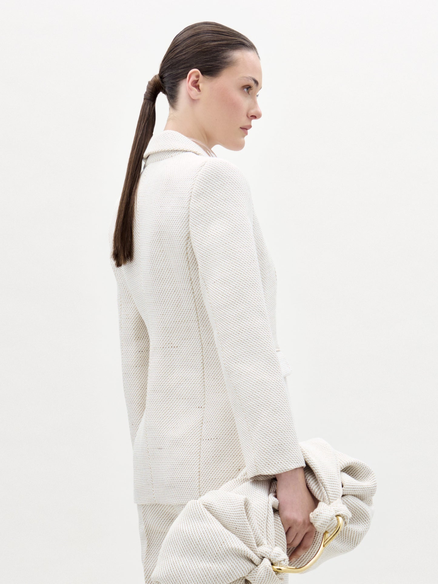 Woman wearing a white textured coat with a plain background