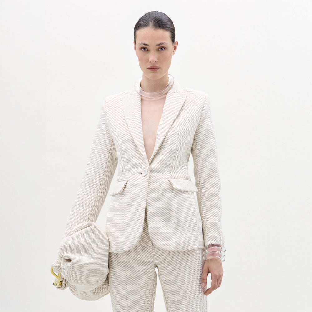 Woman wearing a white textured suit with a plain background