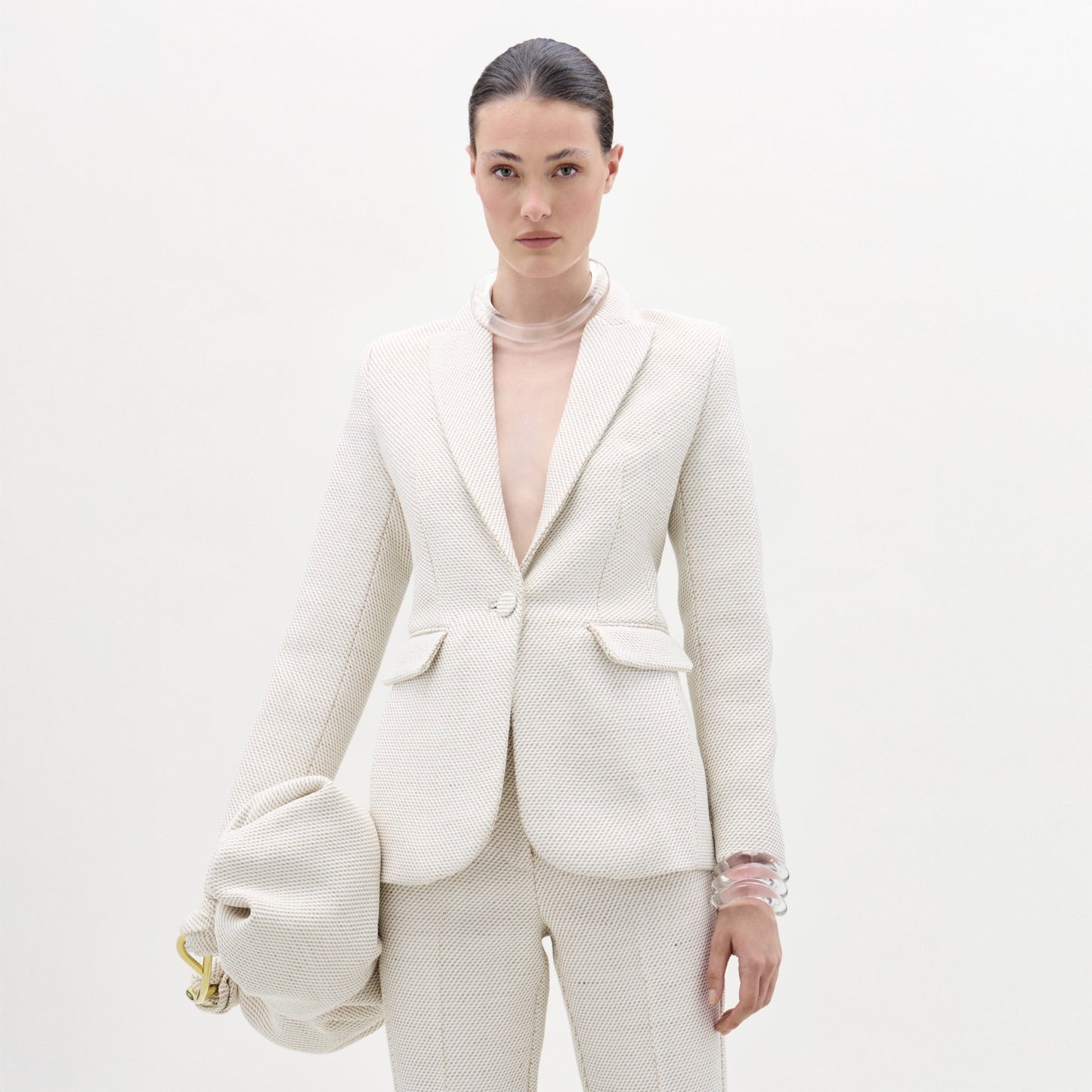 Woman wearing a white textured suit with a plain background