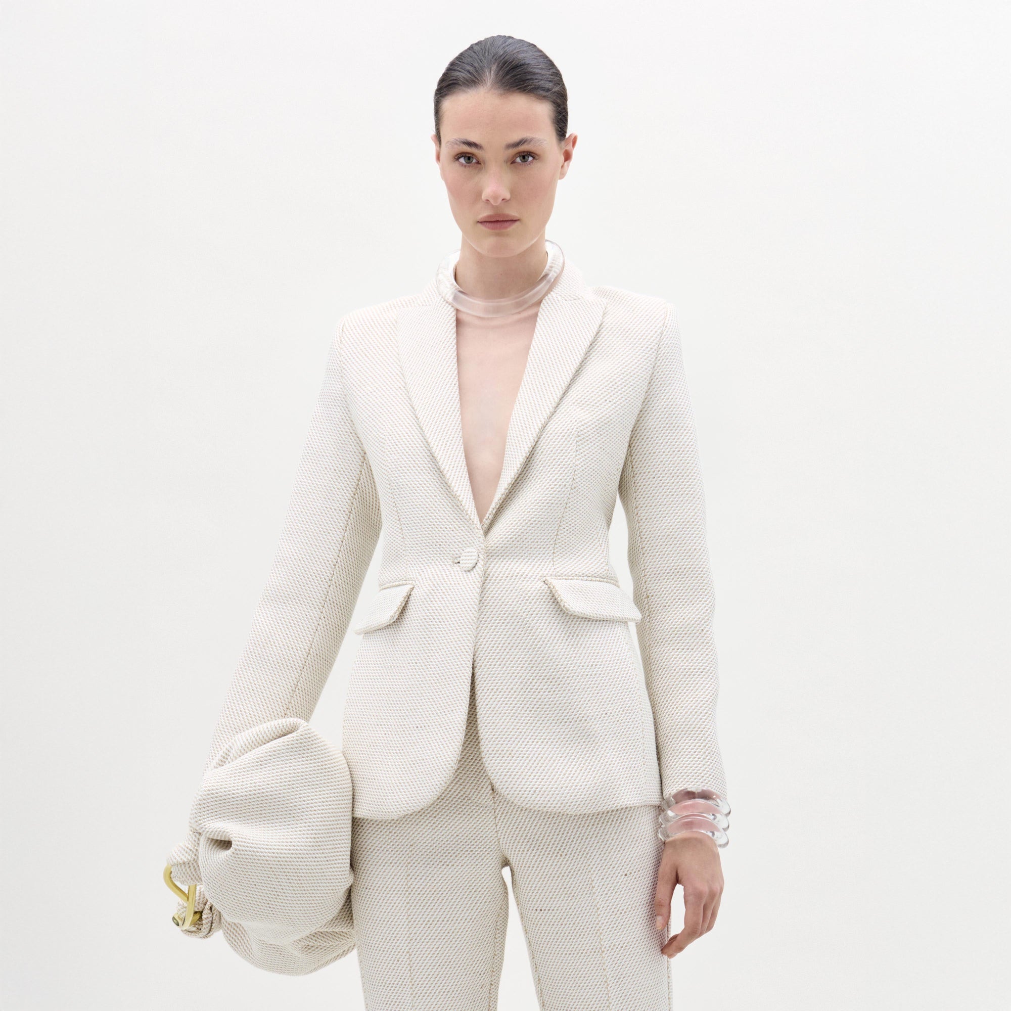 Woman wearing a white textured suit with a plain background