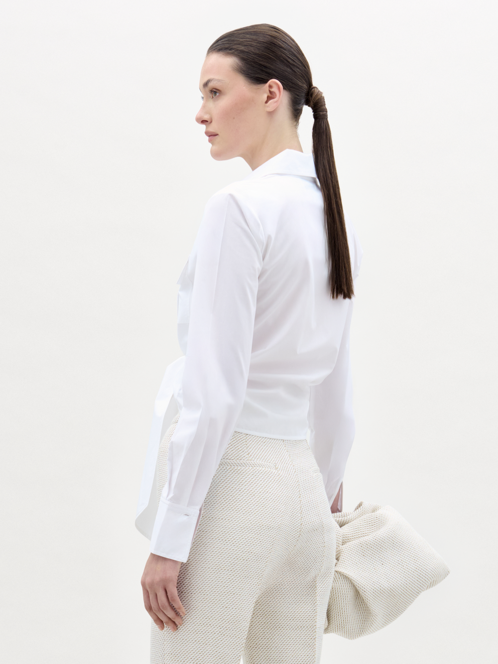 Woman wearing a white shirt and white pants with a white background