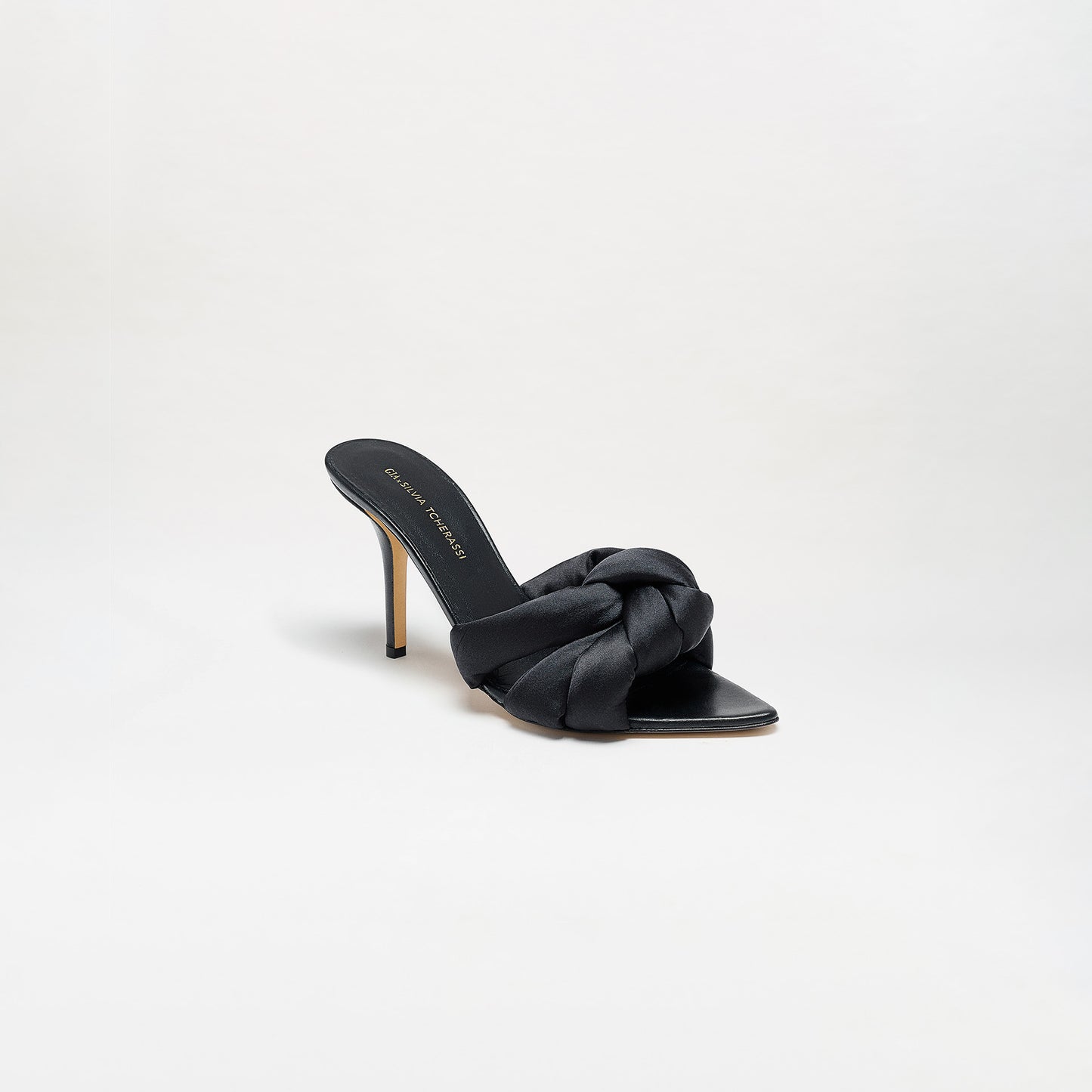 The Ana Heels are single black high-heeled mule sandals featuring a satin braided strap, open toe, thin stiletto heel, and expertly crafted from Italian leather, displayed on a plain white background.