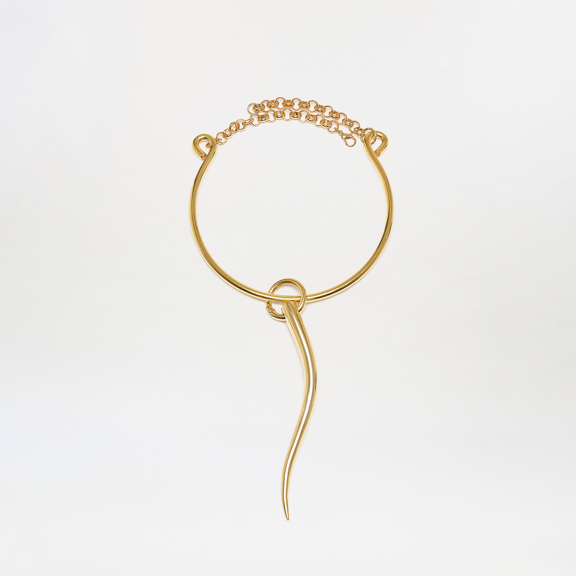 The Melinda Chocker features a gold circular band, decorative chain, two small loops, and a long curved drop pendant hanging from a central knot. Displayed on a plain white background.
