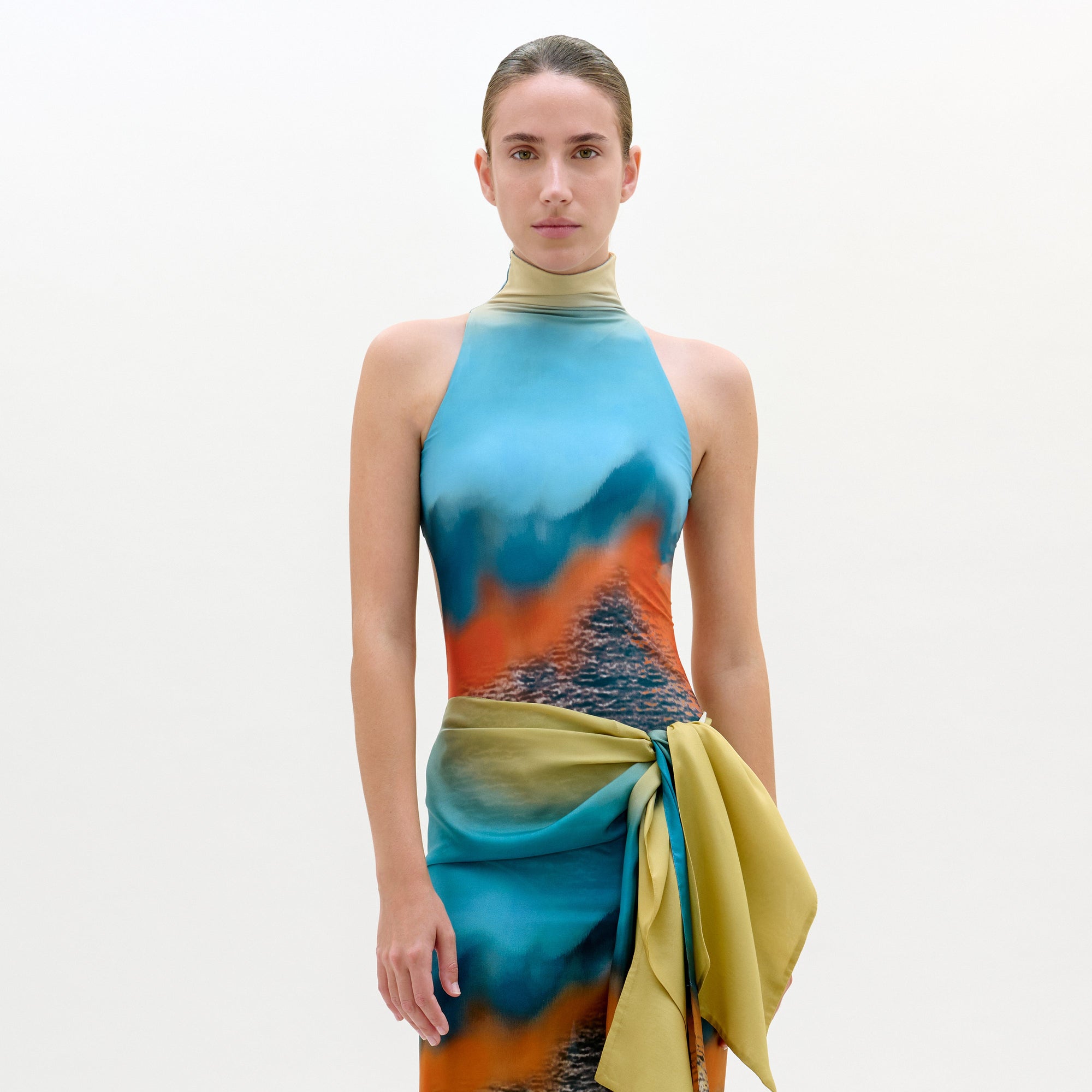 Model wearing a colorful dress with a gradient design on a plain background