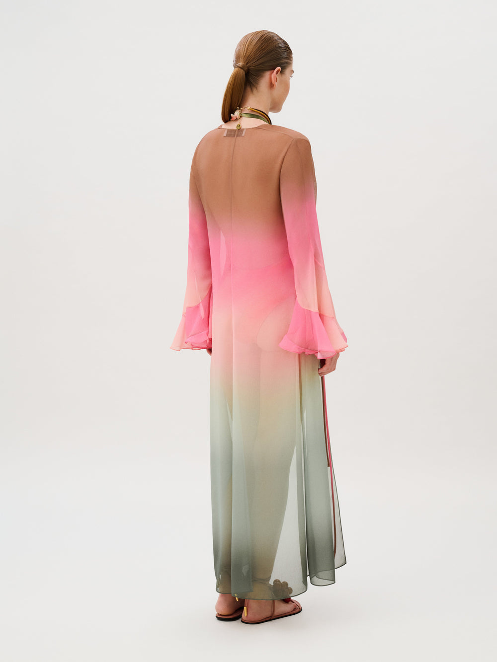 Back view of the Amaris Tunic, a floor-length, sheer chiffon kaftan with an ombré pattern transitioning from brown to pink to pale green, featuring bell sleeves and side slits.