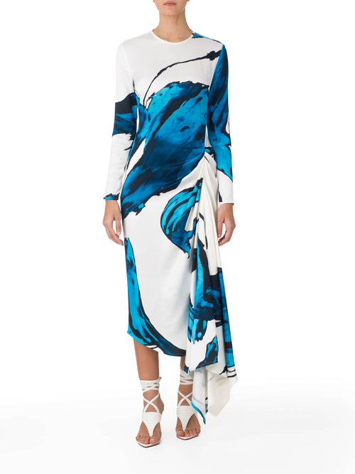 Ananya Dress Multi Abstract Waves with bold blue abstract print design, featuring an asymmetrically draped skirt, displayed on a white background.