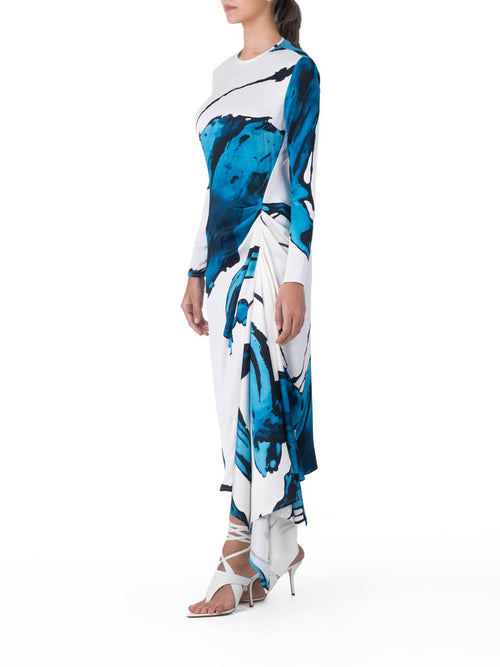 Ananya Dress Multi Abstract Waves with bold blue abstract print design, featuring an asymmetrically draped skirt, displayed on a white background.