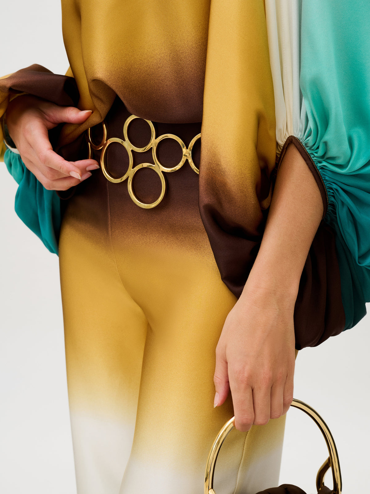 Andie Pant: high-waisted wide pants in Italian silk with a yellow, brown, and teal ombre pattern, cinched with a gold-toned circular link belt.