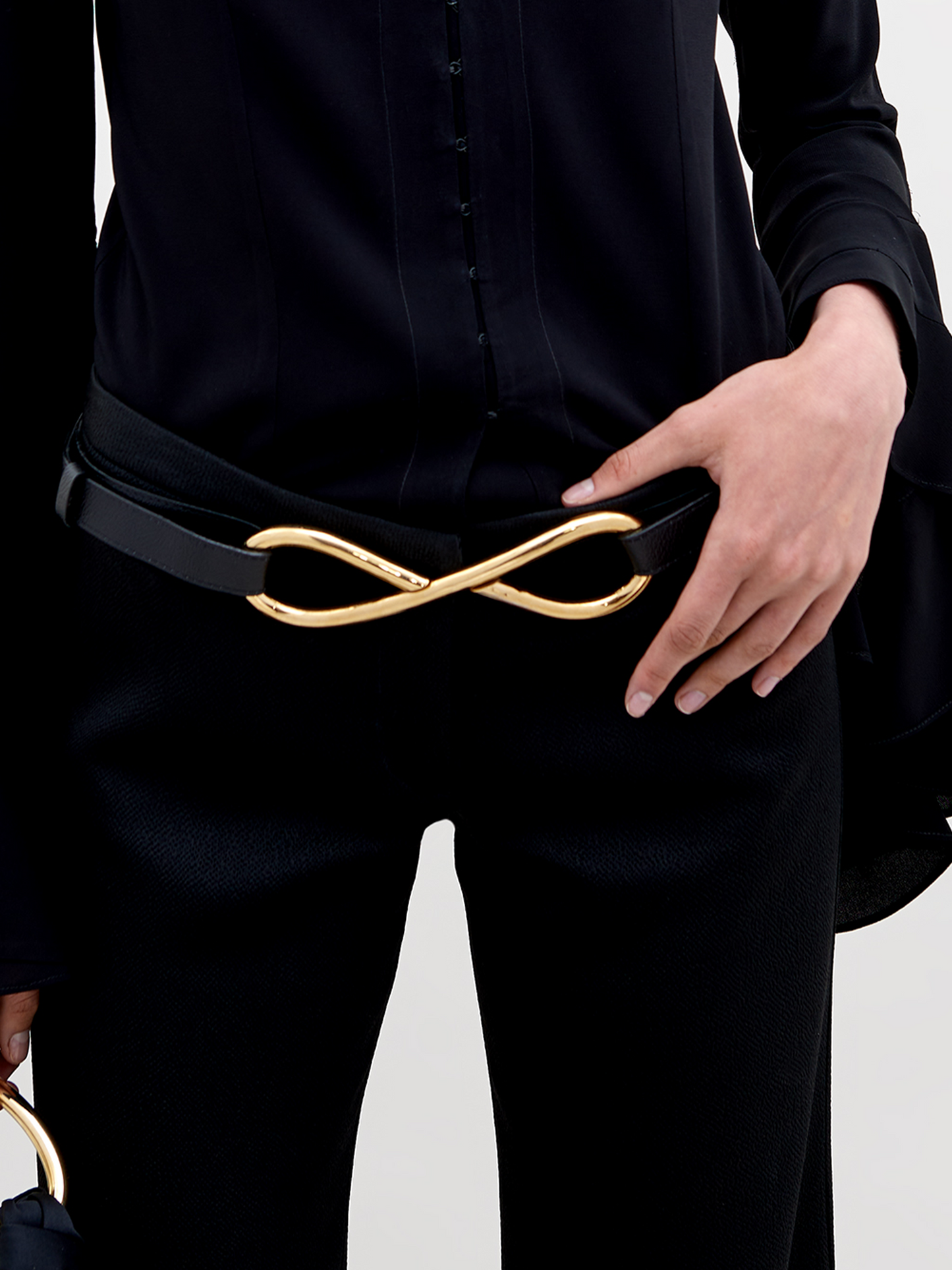 Pre-order the Oihana Belt Black featuring a gold-tone infinity-shaped buckle in the center, available for shipment by November 15th, 2024.