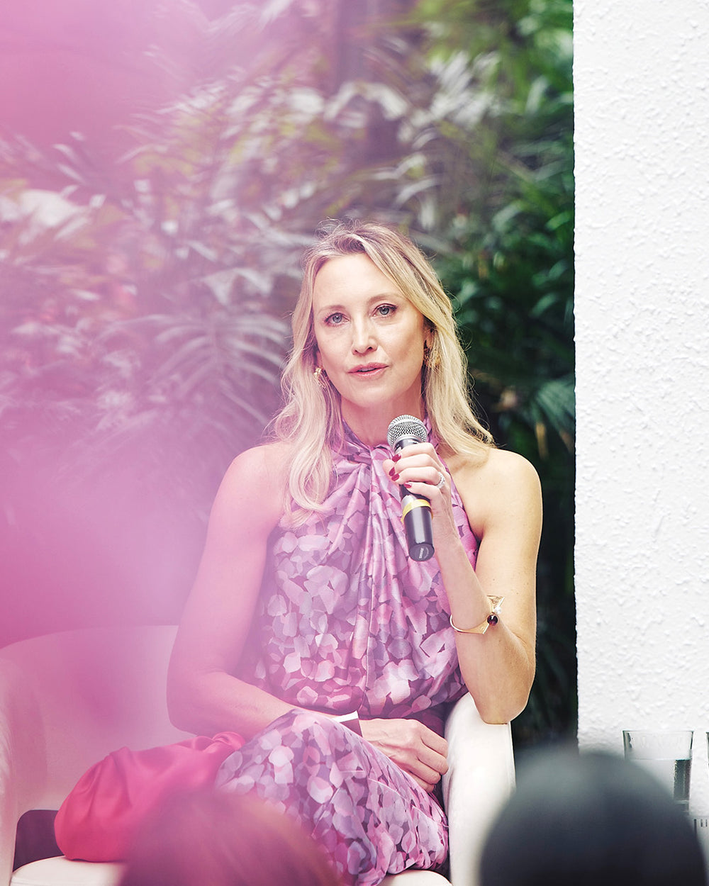Woman in a floral dress holding a microphone outdoors