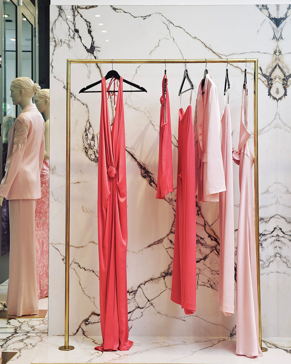 Pink dresses hanging on a rack against a marble wall