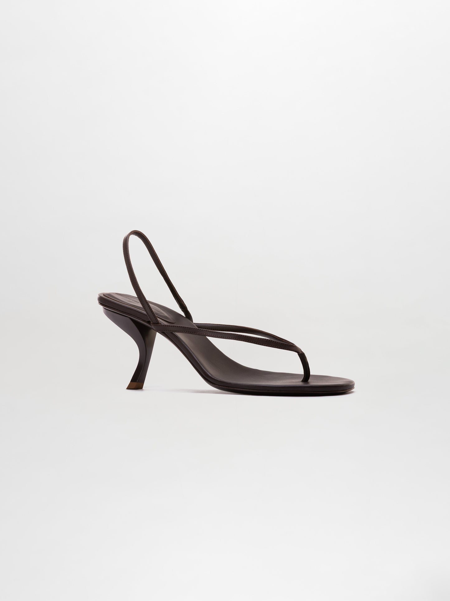 The Aurora Heels are black strappy sandals featuring a thin thong-style toe strap and a curved heel, showcased against a plain light background.