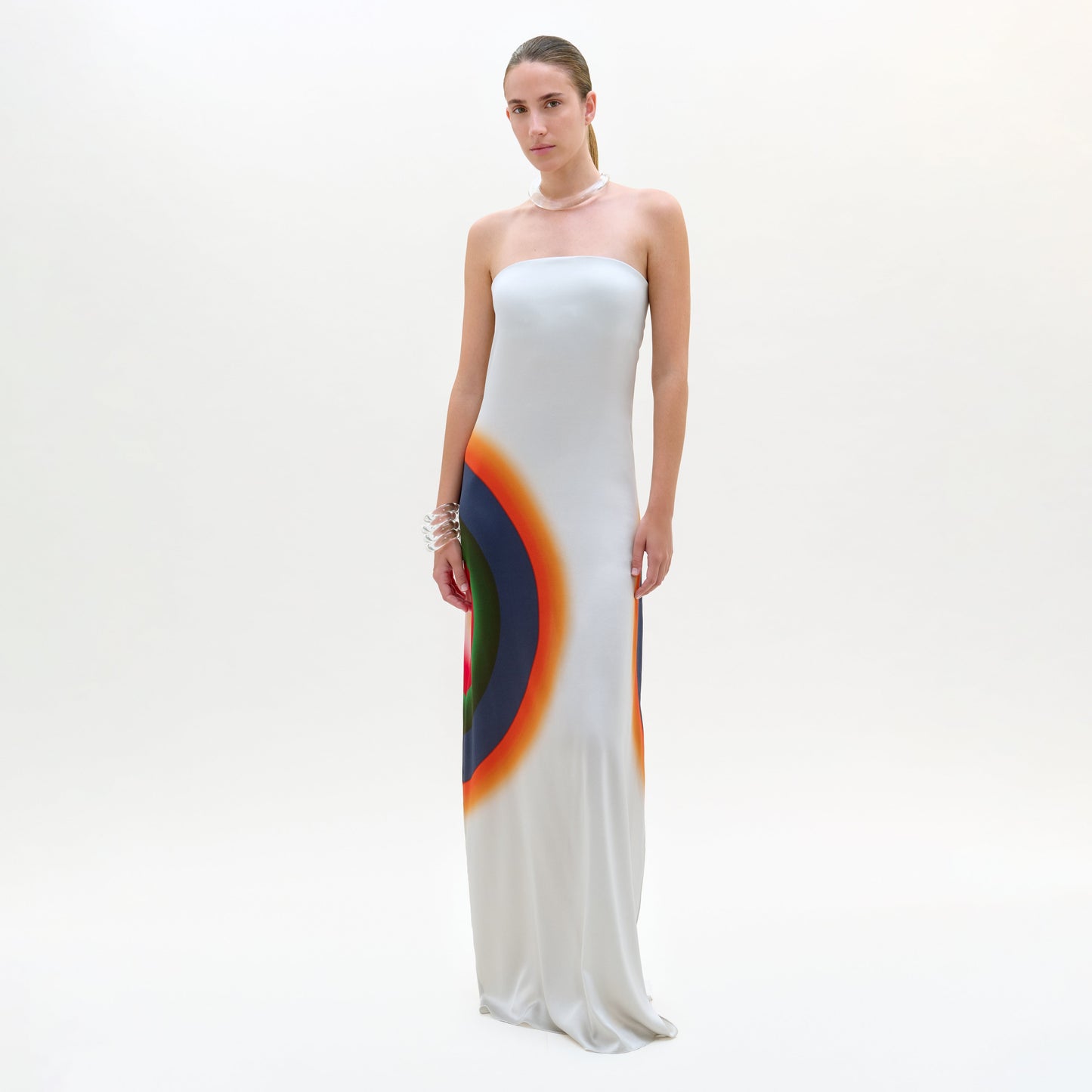 Woman wearing a strapless white gown with a colorful design on a white background
