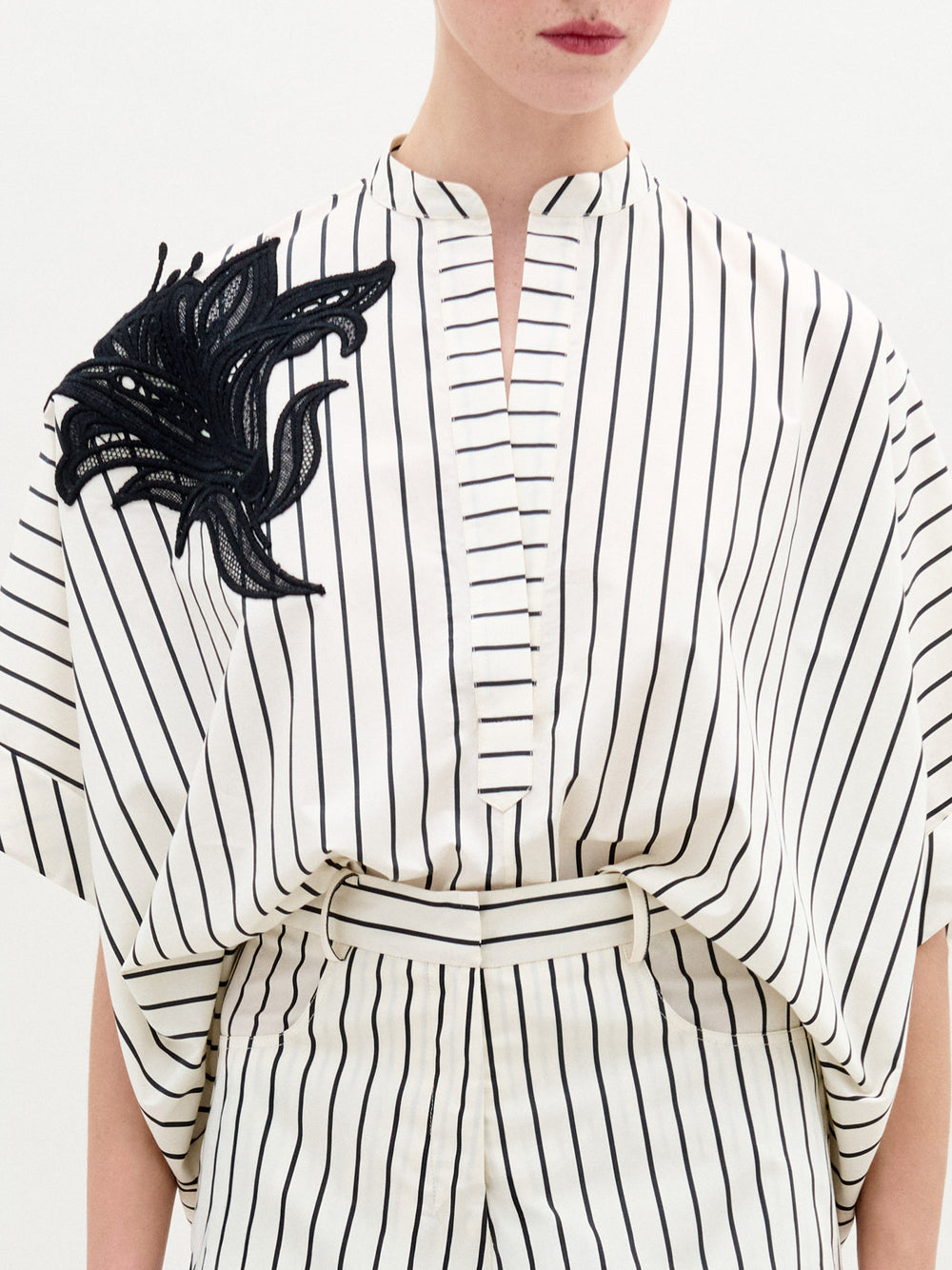 A person wearing the Daia Blouse in color Black White Stripes  on a white background.