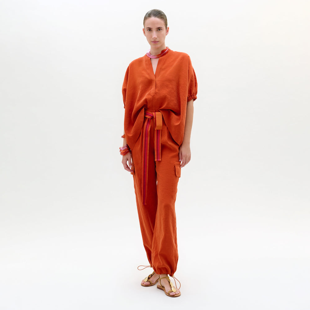 Woman wearing an orange outfit with a belt on a white background
