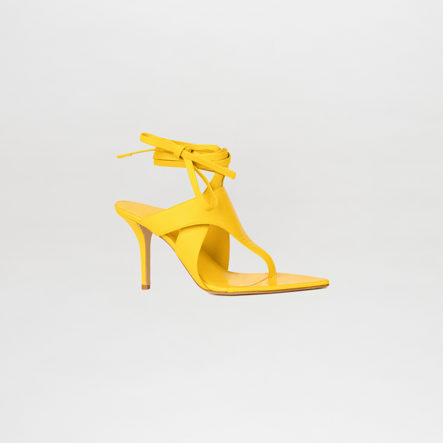 Yellow high-heeled sandal on a light gray background